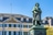 Statue vor historischem Gebäude mit gelben und weissen Fassaden.