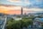 Stadtpanorama bei Sonnenuntergang mit Turm und Bäumen.