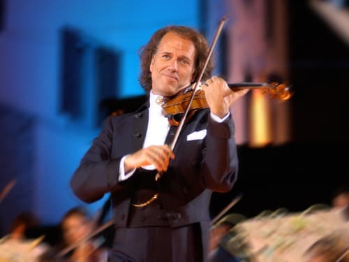 Geiger in Anzug spielt Violine auf Bühne.