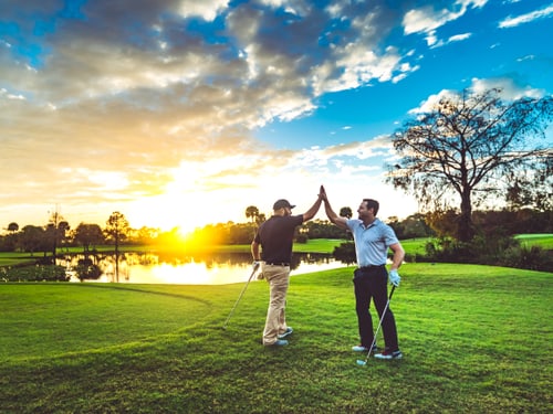 Zwei Männer auf dem Okeeheelee Golfplatz in West Palm Beach klatschen sich ab, Golfschläger in der Hand.