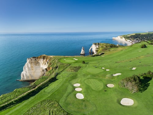 Luftaufnahme des Golfplatzes von Étretat mit grünen Fairways, Sandbunkern und weissen Kreidefelsen an der Küste.