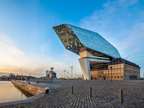 Das Havenhuis in Antwerpen: moderner Glasaufbau von Zaha Hadid über historischer Feuerwache am Hafenbecken.