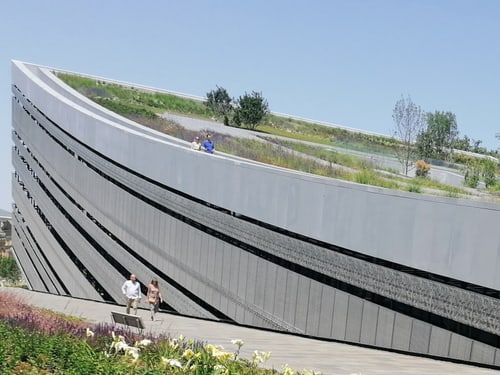 Moderner Bau mit bepflanztem Dach und Gehweg.