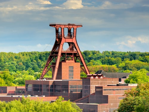 Rote Zeche Zollverein mit grünem Waldhintergrund.