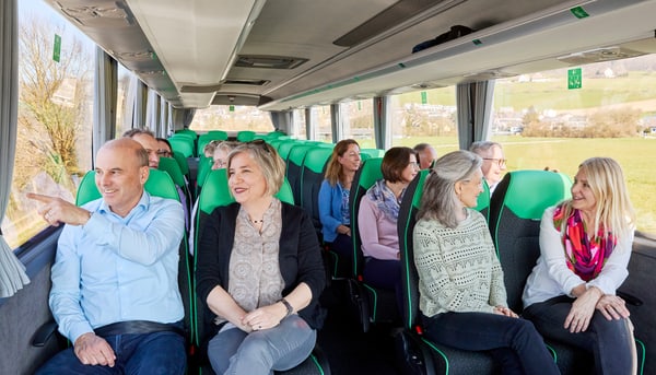 Gruppe von Menschen sitzt lächelnd in einem Reisebus.