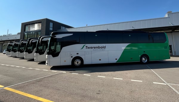 Mehrere geparkte Reisebusse vor einem Gebäude an einem sonnigen Tag.