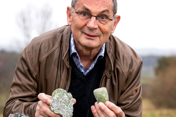 bodenschaetze-am-rhein-1.jpg Älterer Mann im braunen Jacke hält zwei Steine draussen in der Hand.