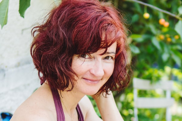 Frau mit rotem Haar vor grünem Hintergrund.