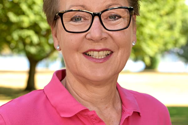 best-of-golf-donau-und-main-1.jpg Person mit Brille in einem pinken Oberteil vor einem Baum im Freien.