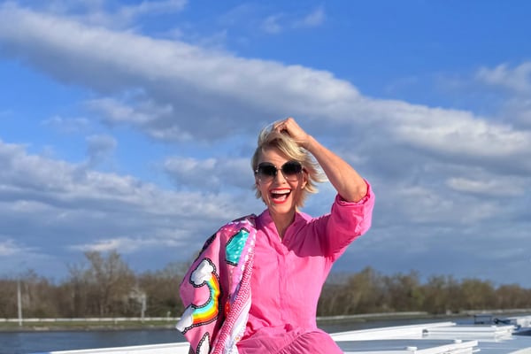 Frau in pinkem Kleid sitzt auf weissem Dach bei sonnigem Wetter.