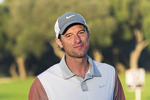 Mann in Golfkleidung auf Golfplatz.