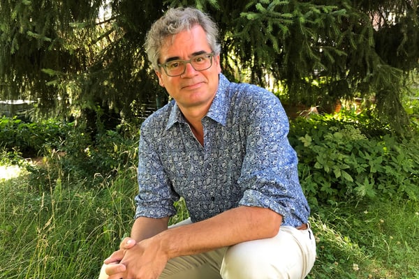 Mann in gemustertem Hemd sitzt im Garten.