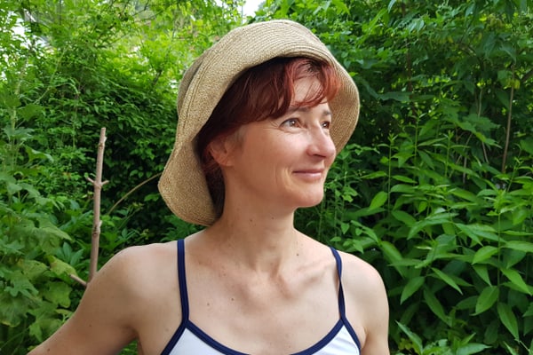 lilo-meier.jpg Person mit Strohhut im Garten, von grüner Vegetation umgeben.