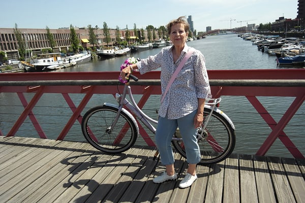 grand-tour-nordische-sommer-cruise-1.jpg Eine Person steht mit einem Fahrrad auf einer Brücke über einem Kanal mit Booten.