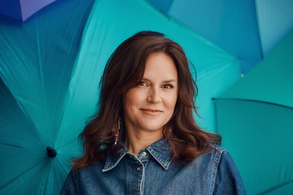 Frau in Jeanshemd vor blauen Regenschirmen.