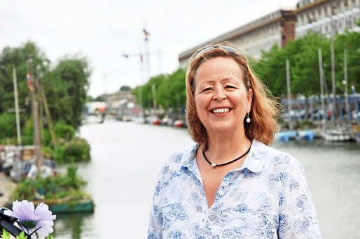 Frau mit Fahrrad auf einer Brücke vor einem Fluss.