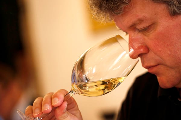 Person riecht an einem Glas Weisswein.