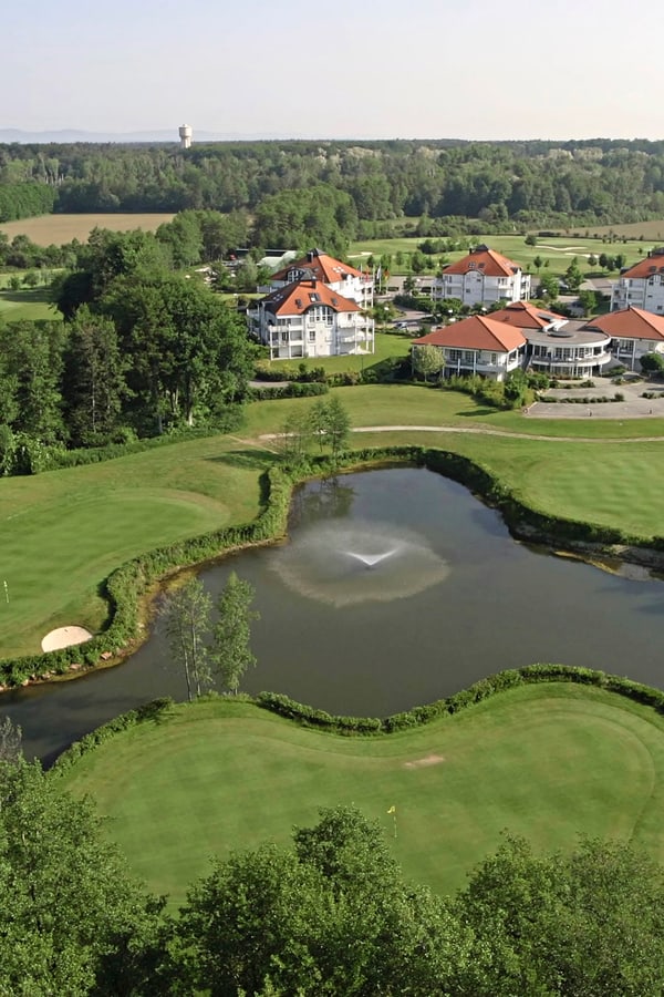 golfclub-soufflenheim.jpg Luftaufnahme eines Golfplatzes mit Teich und Gebäuden im Hintergrund.