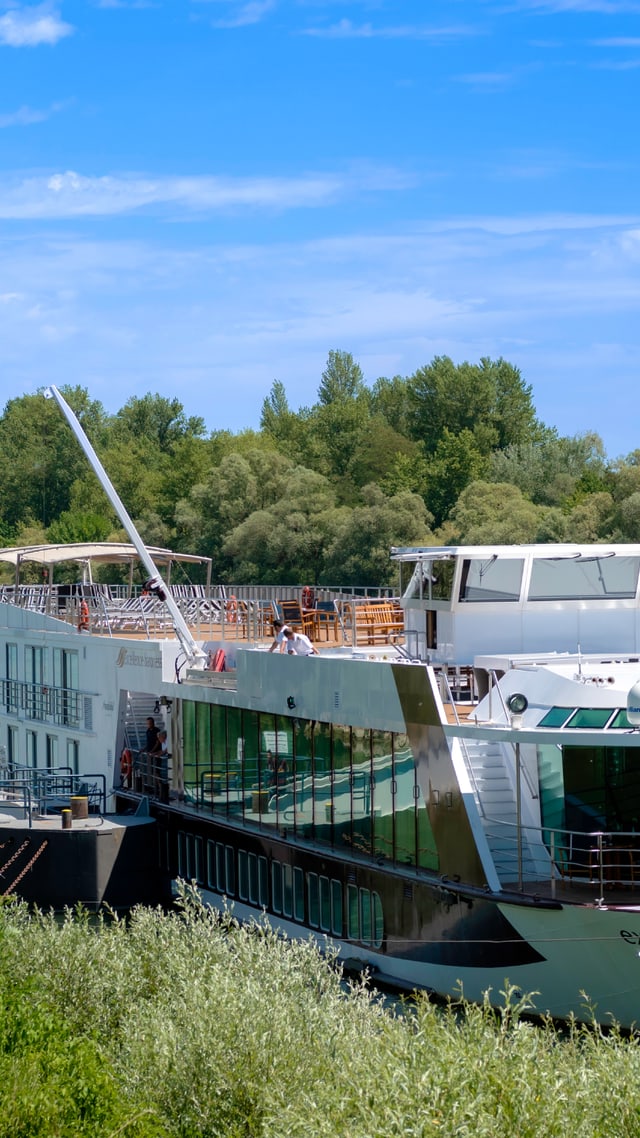Passagierschiff auf einem Fluss mit Bäumen im Hintergrund.