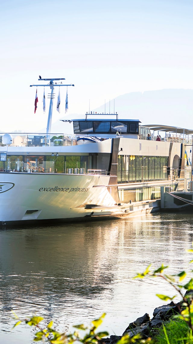 donau-2.jpg Flusskreuzfahrtschiff auf ruhigem Fluss bei sonnigem Wetter.