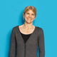Frau mit grauem Cardigan vor blauem Hintergrund.