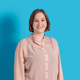 Person mit rosa Bluse vor hellblauem Hintergrund.