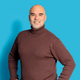 Mann mit braunem Rollkragenpullover vor blauem Hintergrund.