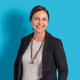 Frau in schwarzem Blazer vor blauem Hintergrund.