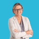 Person mit Brille und hellem Blazer vor blauem Hintergrund.