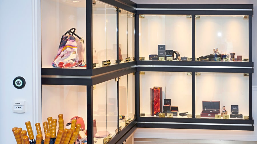 Luxus-Accessoires in Glasvitrine mit Regenschirmständer im Vordergrund.