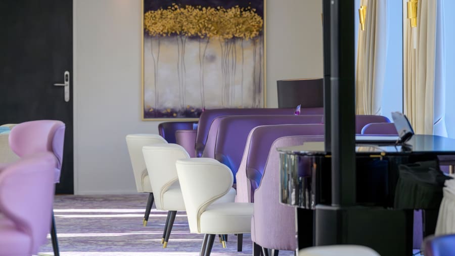 Innenraum eines Restaurants mit lila und weissen Stühlen.