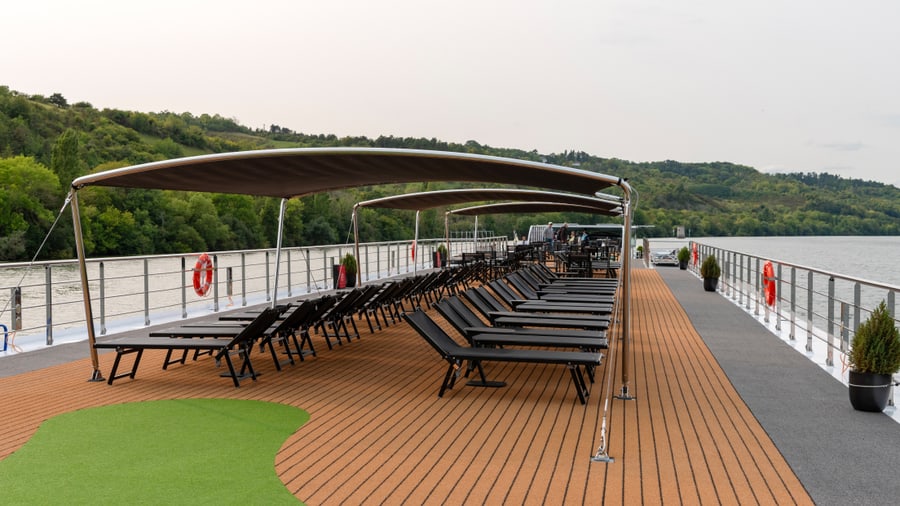 Oberdeck eines Flusskreuzfahrtschiffs mit Liegestühlen und Markise.