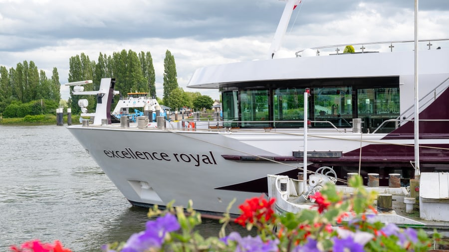 Kreuzfahrtschiff Excellence Royal auf Fluss mit Blumen im Vordergrund.