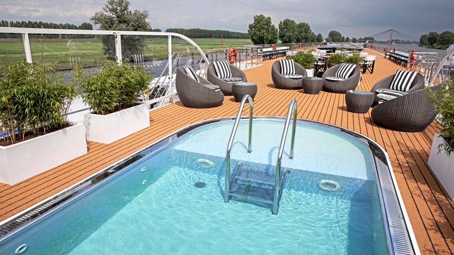 Deck eines Kreuzfahrtschiffs mit Pool und Sitzbereichen.