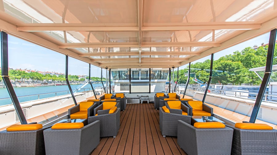 Sonnendeck eines Schiffes mit Sitzgruppen und Flussblick.