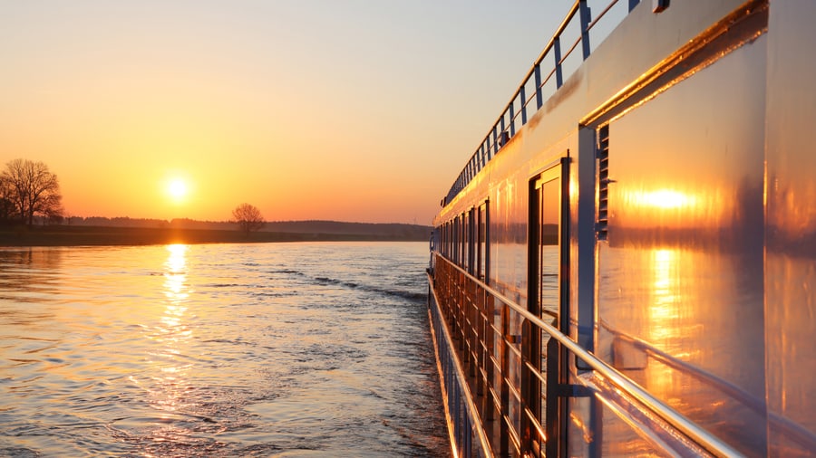 Bootsfahrt auf Fluss bei Sonnenuntergang.