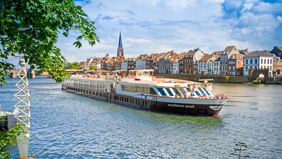Grosses Flussschiff auf einem Fluss mit Stadt im Hintergrund.
