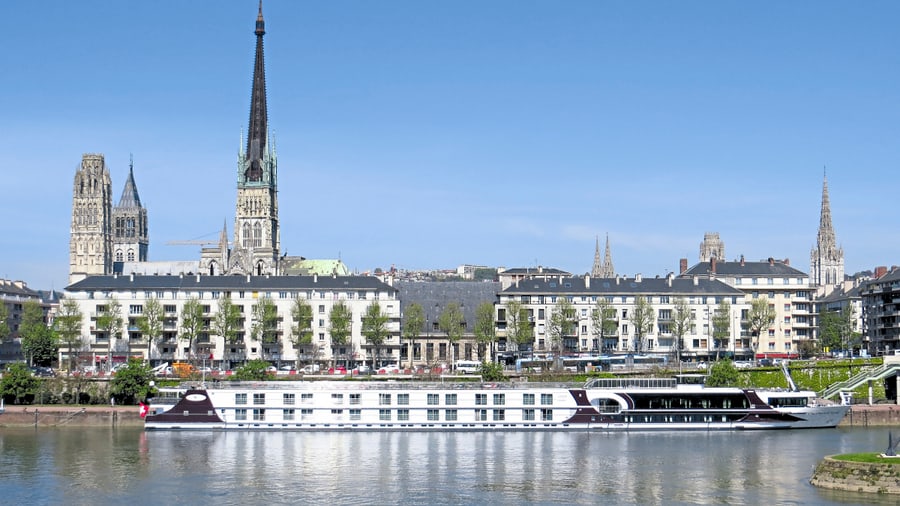 Flusskreuzfahrtschiff vor Stadtsilhouette mit Kirchen.