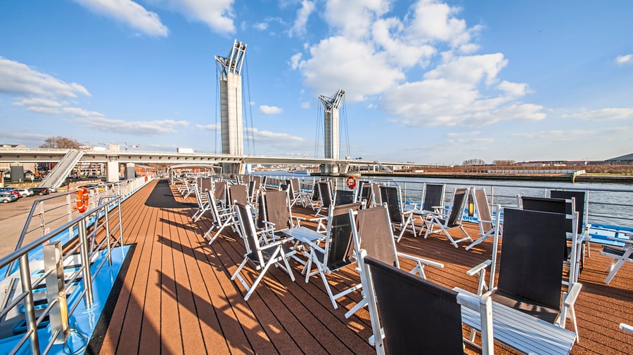 Sonnendeck eines Schiffes mit Stühlen und Blick auf eine Hebebrücke.