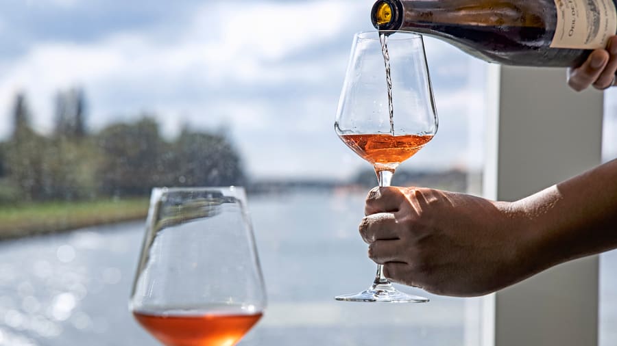 Wein wird in ein Glas am Fluss eingeschenkt.