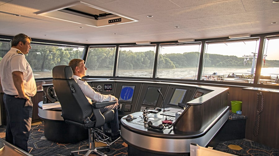 Zwei Männer im Schiffssteuerhaus mit Flussblick.