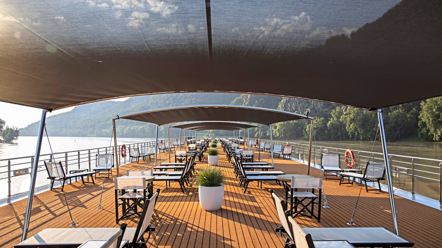 Deck eines Flusskreuzfahrtschiffs mit Sonnendächern und Liegestühlen.