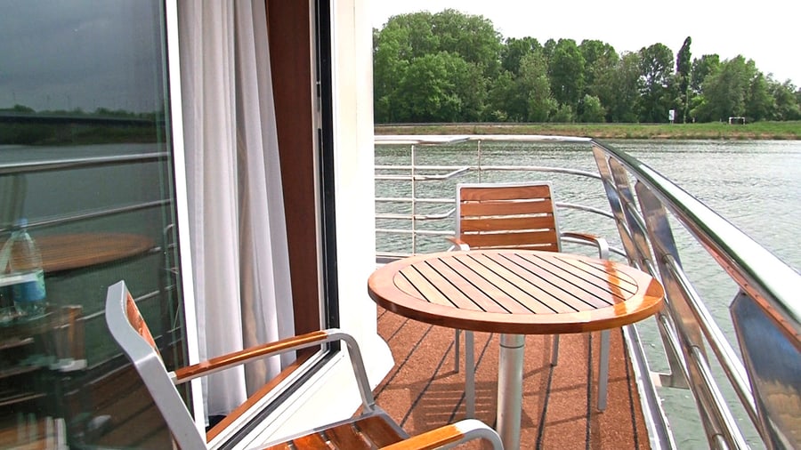 Holztisch und Stühle auf einem Flusskreuzfahrtschiffdeck.