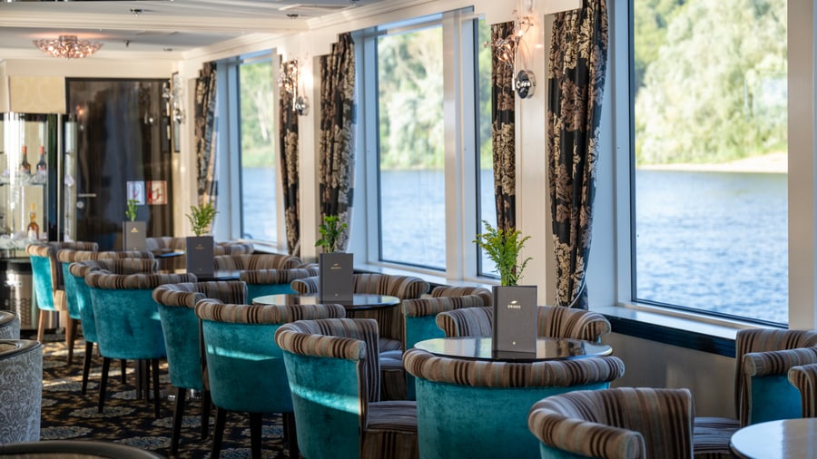 Elegantes Restaurant mit Flussblick und blauen Polstersesseln.