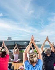Menschen, die im Freien Yoga machen, mit den Armen über dem Kopf.