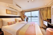 Crewmitglied richtet Bett in Kabine der Excellence Pearl, Blick durch Panoramafenster auf Fluss und Ufer.