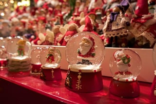 vier-staedte-maerchenhaft-magisch-8.jpg Weihnachtsschneekugeln mit Weihnachtsmann- und Engelmotiven auf rotem Tisch.