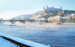 adventsflusszauber-main-7.jpg Alte Brücke und Festung am Fluss in winterlicher Landschaft.
