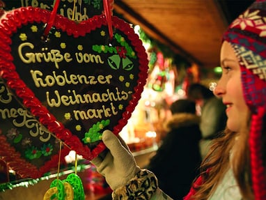 Frau betrachtet Lebkuchenherz auf Koblenzer Weihnachtsmarkt.