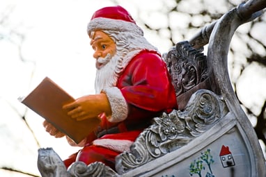 Weihnachtsmannfigur in Schlitten liest Buch.